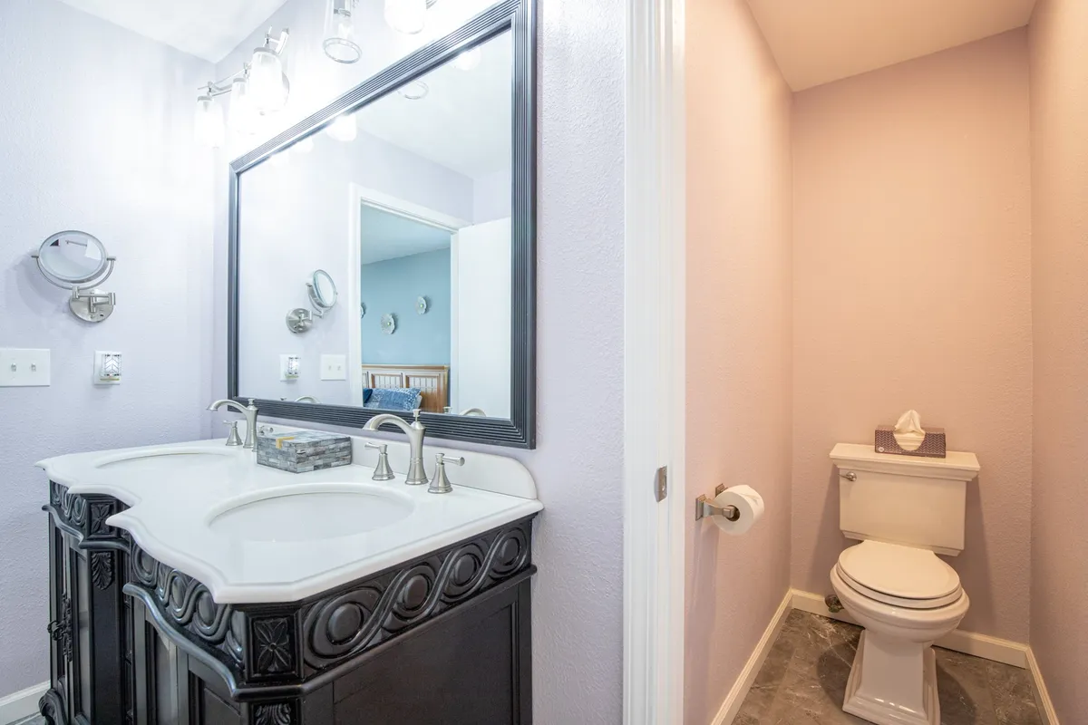 A modern bathroom with a double sink vanity, a large mirror, and contemporary fixtures. There is a dedicated toilet area, clean lines, and a calming color palette, providing a spa-like experience for guests.