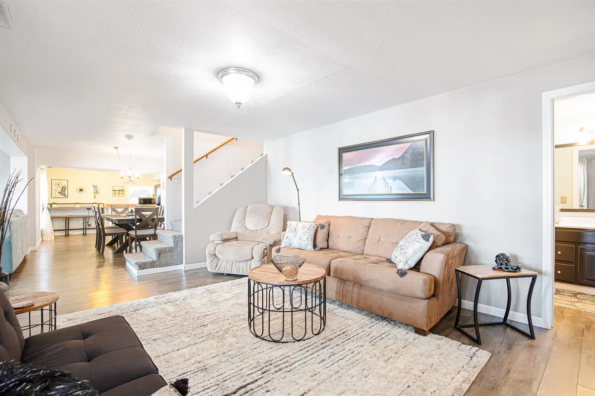 A welcoming living space with a comfortable sofa, coffee table, and visible dining area in the background. The walls are adorned with art, and the atmosphere is inviting, perfect for entertaining guests or family gatherings.