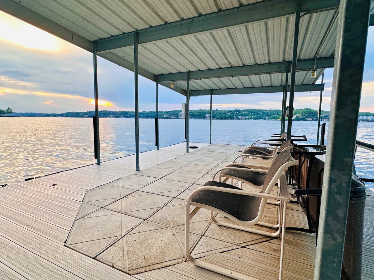 This image captures a peaceful lakeside seating area positioned to enjoy unobstructed sunset views. The scene includes the lake glowing with reflected light, a comfortable sitting spot, and the natural serenity of dusk settling in, inviting relaxation and contemplation.